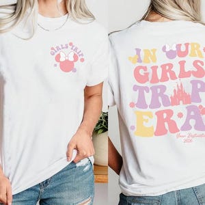A white t-shirt with a graphic design featuring Minnie Mouse and the text "Girls Trip" on the front, and "In Our Girls Trap Era" on the back.