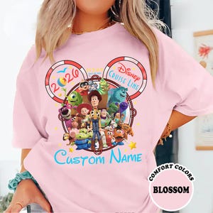 A woman wearing a pink t-shirt with a Disney-themed design featuring characters from the Toy Story movie.