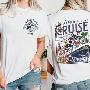 A white t-shirt with a Disney Cruise-themed design on the back, featuring characters such as Minnie Mouse, Mickey Mouse, Donald Duck, and Donald Duck's ship.