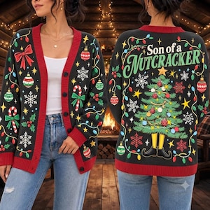 Puede incluir: Un cárdigan de punto negro con tapeta de botones y puños rojos, decorado con adornos navideños, copos de nieve y bastones de caramelo. La espalda muestra un árbol de Navidad con piernas de elfo amarillas y el texto Son of a NUTCRACKER.