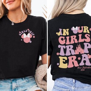 a woman wearing a black t-shirt with a graphic design on the back. The design includes text and a Minnie Mouse character, and it appears to be a promotional or merchandise item related to a girls' trip or a Disney-themed event.