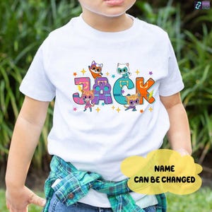 May include: White t-shirt with the name "JACK" in colorful letters, each letter featuring a cartoon cat character. The shirt has a design with stars and the text "NAME CAN BE CHANGED".