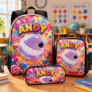 Op de afbeelding: Een set bestaande uit een rugzak, lunchtas en etui met een kleurrijk snoeppatroon, lolly's, een circustent en een paars lachend personage. Elk item toont de naam ANDY in dikke gele letters tegen een levendige achtergrond.
