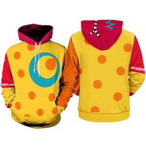 May include: A yellow hoodie featuring orange polka dots, a large teal circular graphic on the front, and a magenta hood. The back of the hood displays a black and white striped pattern with a teal zigzag line. The sleeves are orange and magenta.
