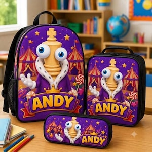 Peut inclure: Un ensemble composé d'un sac à dos, d'un sac à déjeuner et d'une trousse violet, illustré d'un personnage de roi aux échecs avec de grands yeux, une couronne et une cape. Le décor montre un chapiteau, des étoiles et des bonbons. Le nom ANDY est inscrit en jaune.