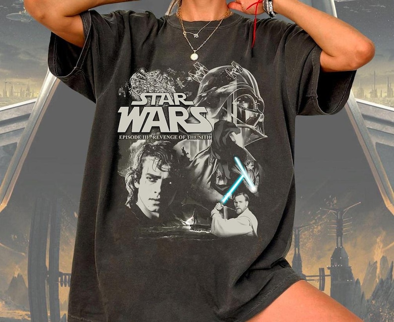 a man wearing a star wars t - shirt holding a light saber