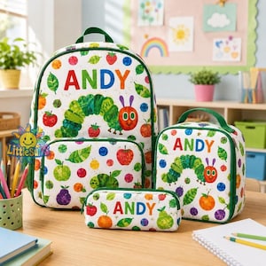 May include: A white backpack, lunch bag, and pencil case set featuring a colorful pattern of fruits, leaves, and the caterpillar character from The Very Hungry Caterpillar. Each item is personalized with the name ANDY in bold, multicolored letters.