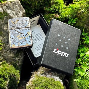 May include: A silver-tone Zippo Armor lighter featuring an intricate blue and gold dragon engraving, displayed in an open black presentation box with a white authentication card that includes the text Zippo and Armor case.