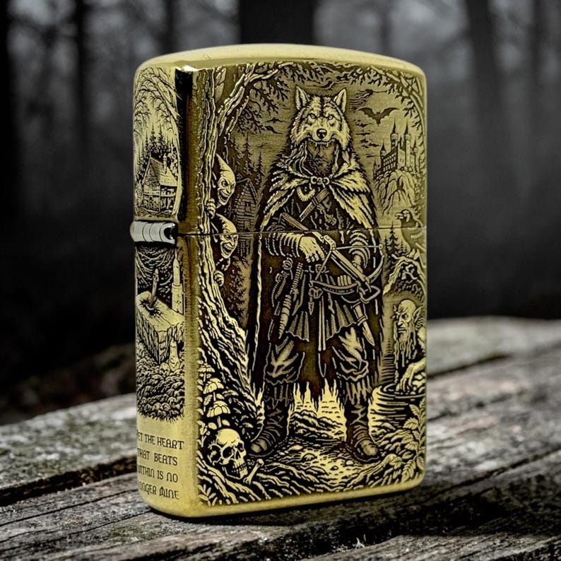 May include: A brass-colored lighter with an engraved design featuring a wolf-like figure in a cloak, holding a crossbow. The design includes a skull, forest elements, and text. The lighter is rectangular and has a hinged lid.