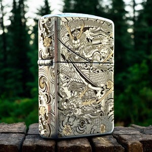 May include: A rectangular metal lighter with a polished silver finish featuring intricate laser-engraved details of a samurai warrior in armor, a large dragon, a traditional pagoda building, swirling wave patterns, and small floral accents.
