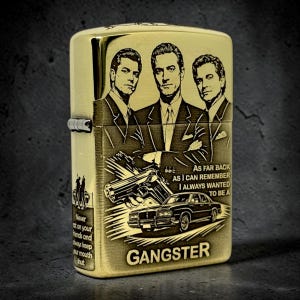 May include: A gold-toned metal flip-top lighter featuring an engraved illustration of three men in suits, a handgun, and a classic car. The text reads: As far back as I can remember I always wanted to be a GANGSTER. A smaller side panel shows two figures.
