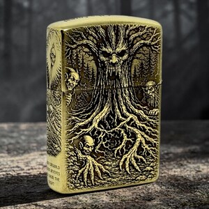 May include: A brass-colored lighter with an intricate engraved design. The design features a gnarled tree with a face, surrounded by forest imagery and grotesque figures. The lighter has text on the side that reads "Emerald...revives...from the...night."
