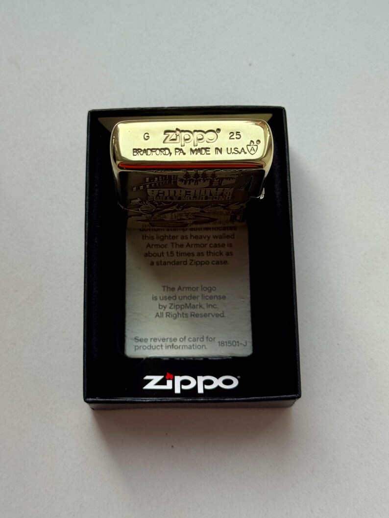 Pu&ograve; includere: Un accendino Zippo color oro in una scatola nera. L'accendino &egrave; contrassegnato con "Zippo 25 BRADFORD, PA. MADE IN U.S.A." e include una grafica. La scatola mostra anche il logo Zippo e le informazioni sul prodotto.