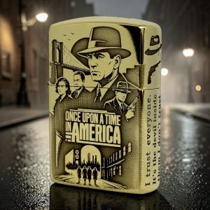 Pu&ograve; includere: Un accendino color oro con un'incisione dettagliata di personaggi e scene di "C'era una volta in America". Il design include il testo "Once Upon a Time in America" e la citazione "Mi fido di tutti. &Egrave; il diavolo dentro di loro in cui non mi fido."