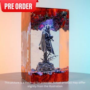 May include: A resin sculpture featuring a figure from "The Crow" perched atop a detailed base. The sculpture is encased in a rectangular block with red and orange accents. The top banner reads "PRE ORDER".