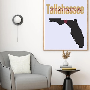 May include: A print of the state of Florida with a red heart over Tallahassee. The text "Tallahassee" is in gold letters and the text "Florida" is in red letters.