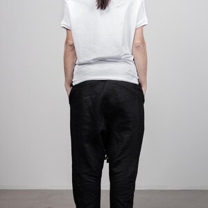 May include: A white short-sleeved shirt with a cowl neck and black pants.