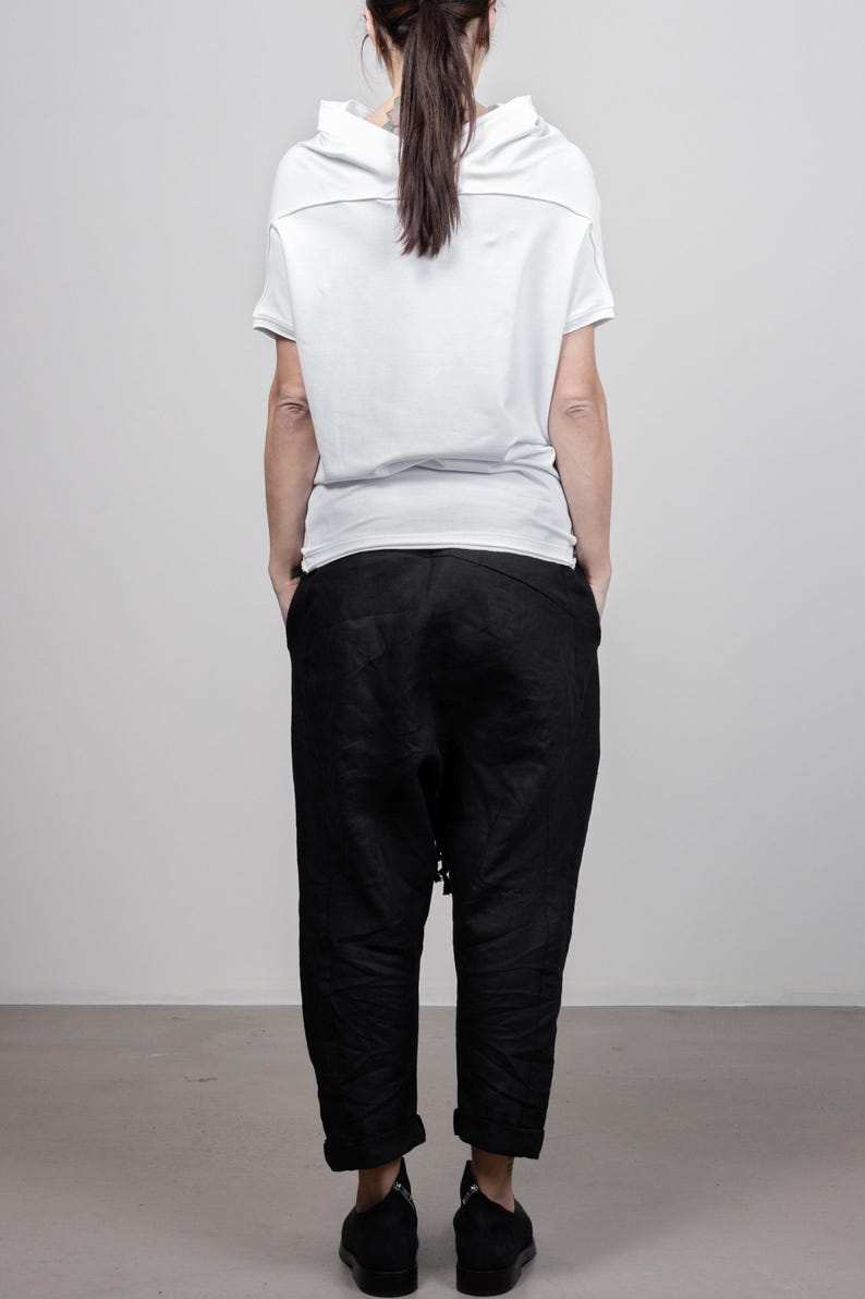 May include: A white short-sleeved shirt with a cowl neck and black pants.