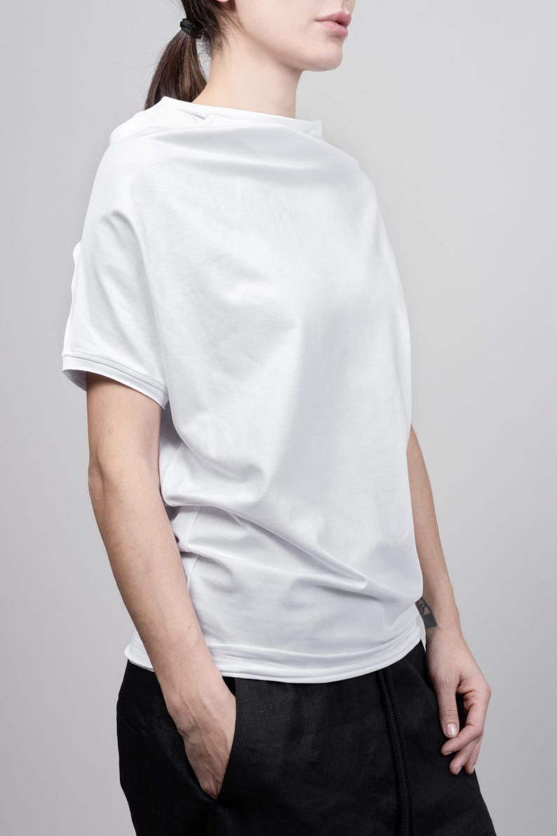 May include: A white, loose-fitting t-shirt with a slightly off-the-shoulder neckline. The shirt is made of a soft, comfortable fabric and has a relaxed fit.
