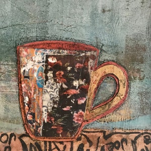 May include: A red and yellow coffee mug with a floral pattern and the words "The Java" written on a brown surface.
