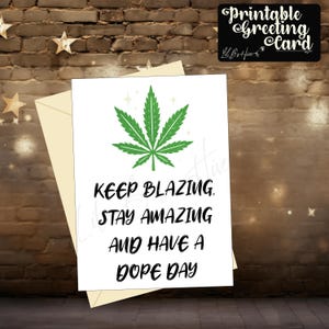 May include: A white greeting card with a green cannabis leaf design and the words "Keep Blazing, Stay Amazing, And Have a Dope Day" in black. The card is inside a cream envelope. A black sign says "Printable Greeting Card".