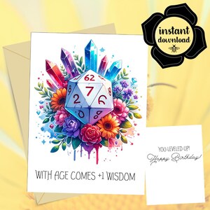 May include: A greeting card featuring a white twenty-sided die surrounded by colorful flowers and crystals. The text reads "WITH AGE COMES +1 WISDOM" at the bottom. A separate white card displays the text "YOU LEVELED UP! Happy Birthday!"