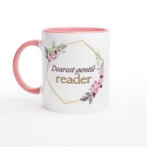 May include: White ceramic mug with a pink rim and handle. The mug features a gold geometric frame with pink floral accents and the text "Dearest gentle reader" in gold lettering.