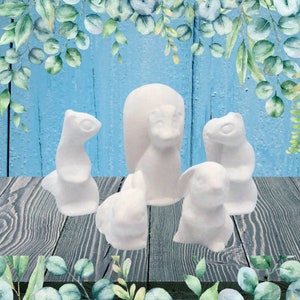 May include: Five white ceramic squirrel figurines, including one larger squirrel standing upright and four smaller squirrels in various poses. The figurines are arranged on a wooden surface.