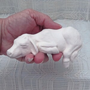 May include: White ceramic figurine of a sleeping pig. The pig is lying on its side with its legs curled up. The figurine is about 6 inches long.