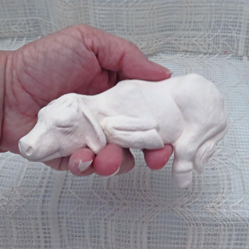 May include: White ceramic figurine of a sleeping pig. The pig is lying on its side with its legs curled up. The figurine is about 6 inches long.