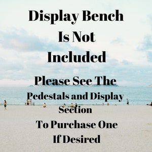 May include: Text on a beach scene background that reads: "Display Bench Is Not Included. Please See The Pedestals and Display Section To Purchase One If Desired."