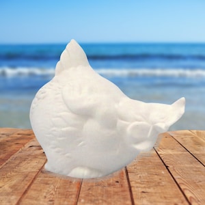 Może przedstawiać: Biała ceramiczna figurka kurczaka z fakturowaną powierzchnią. Kurczak siedzi z głową pochyloną na bok.