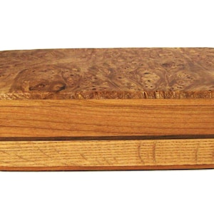 May include: A rectangular wooden box featuring a lid with a prominent burl wood grain pattern in shades of brown and tan. The body of the box is constructed from horizontal layers of light and medium-toned wood with a thin dark brown accent stripe.