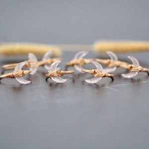 May include: A set of six delicate gold wire wrapped rings with clear crescent moon shaped quartz stones.