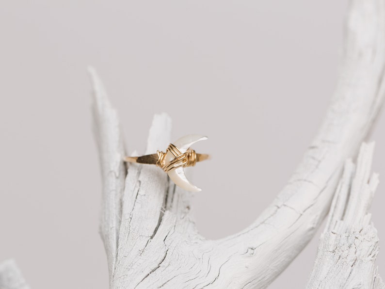 K&ouml;nnte beinhalten: Ein Ring aus goldfarbenem Draht mit einer wei&szlig;en, halbmondf&ouml;rmigen Muschel.