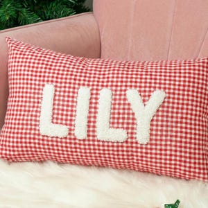 A red and white checkered pillow with the name "Lily" embroidered on it.