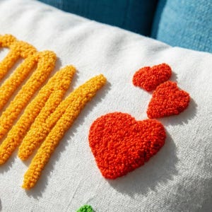 a close-up view of a white fabric with a vibrant red heart-shaped embroidered patch and a yellow heart-shaped embroidered patch.