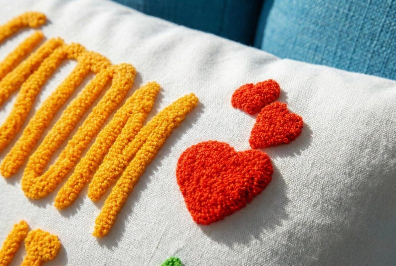 a close-up view of a white fabric with a vibrant red heart-shaped embroidered patch and a yellow heart-shaped embroidered patch.