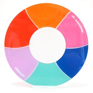 May include: A circular, flat decorative object featuring a vibrant, multi-colored design divided into six distinct segments. The colors include orange, pink, blue, teal, light purple, and red, all surrounding a solid white circular center.