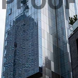 May include: A tall, modern glass and metal building with the word "PROOF" in large, black letters across the front.