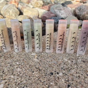 May include: Ten different lip balm tubes with various flavors, including Apple Slice, Sault St. Marie Strawberry, Mt. Pleasant Mango Peach, Beaver Island Blueberry, Mackinac Island Mint, Charlevoix Crumb Cake, Bloomfield Blackberry Pom, Traverse City Cherry Berry, and Grand Rapids Green Tea.