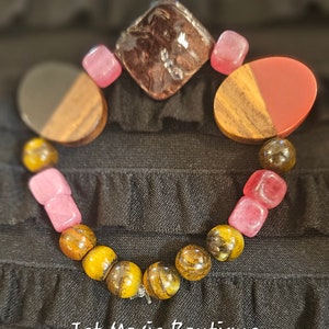 May include: A bracelet with tiger's eye beads, pink and red gemstone beads, and wooden beads. The bracelet has a silver clasp.