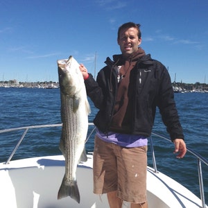 Fisherman holding a large striped bass off Newport Rhode Island