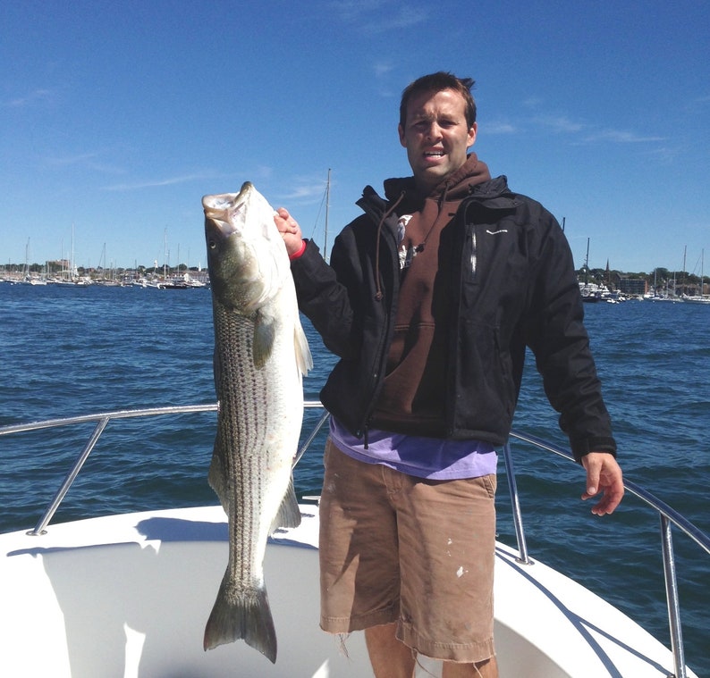 Fisherman holding a large striped bass off Newport Rhode Island
