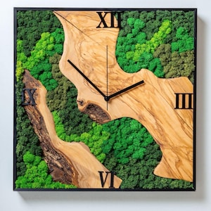 Könnte beinhalten: Quadratische Wanduhr mit schwarzem Rahmen, mit einem Naturholzdesign mit schwarzen römischen Ziffern und Zeigern. Der Hintergrund ist ein lebendiges grünes Moos.