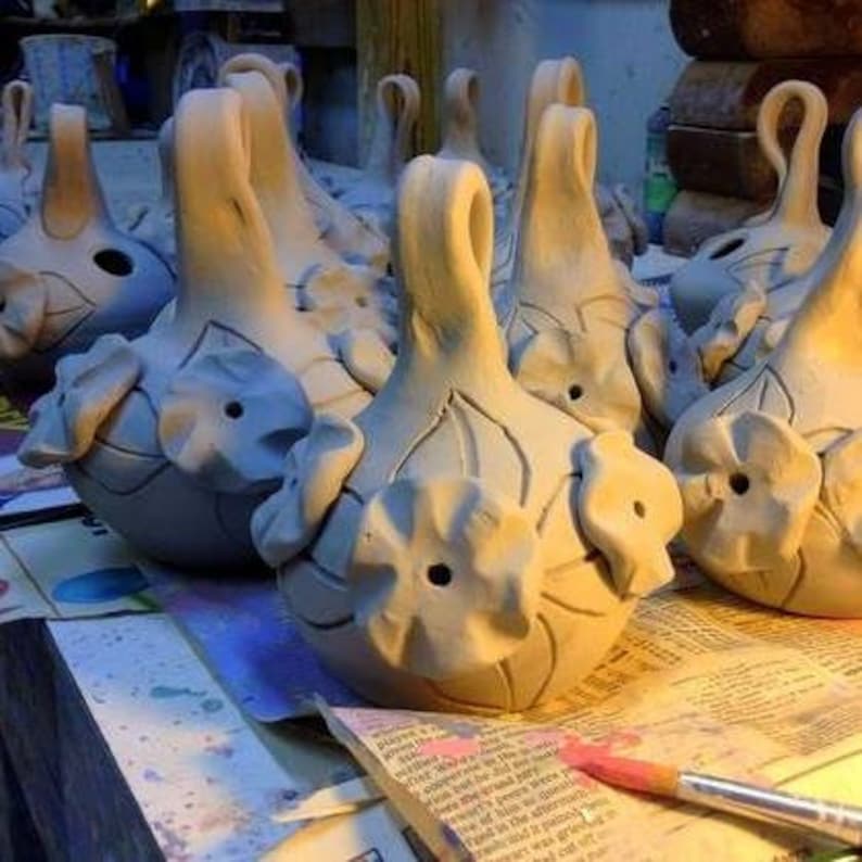 May include: A group of ceramic flower-shaped hanging ornaments with a light blue glaze. The ornaments have a loop at the top for hanging and are decorated with raised flower details.