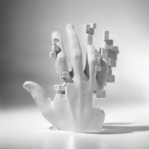 Puede incluir: Una escultura blanca de una mano con un efecto pixelado. Los dedos y la palma están parcialmente fragmentados, con pequeños bloques cuadrados que parecen desprenderse de la forma. La escultura se encuentra sobre un fondo suave y degradado.