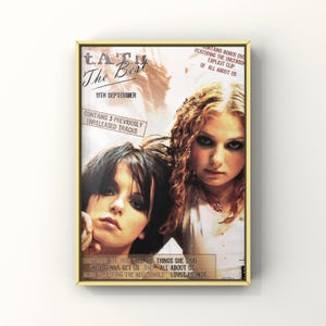 May include: A framed poster featuring two women with dark eye makeup. The poster is for the album "t.A.T.u. The Best", with text indicating it includes unreleased tracks and a bonus DVD.