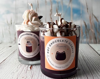 Pode incluir: Dois frascos de vidro com líquido castanho e creme batido branco no topo. Os frascos são etiquetados como 'Hot Chocolate Candle' com um logotipo que diz 'Lumine' e 'Light Up Your Life'. Os frascos estão sobre uma superfície de madeira.