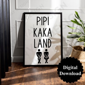 Puede incluir: Señal imprimible en blanco y negro con el texto "Pipi Kaka Land" y dos figuras de palo que representan a un hombre y una mujer. La señal está enmarcada en un marco negro y está sobre un suelo de madera.